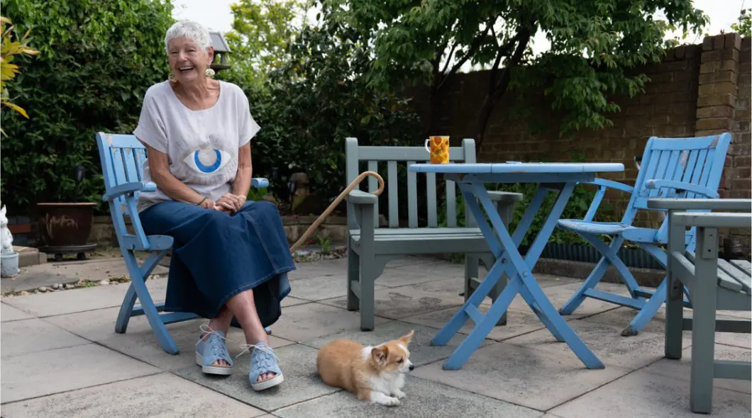 A woman sat on a chair in a garden with a dog