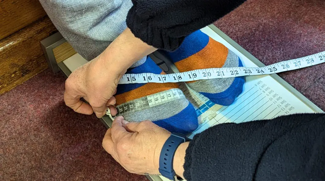 Someone in stripey socks getting their feet measured with a tape measure