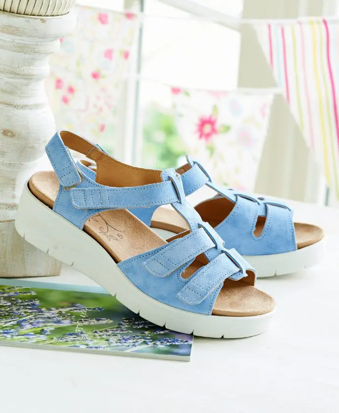 A pair of blue wedge strap sandals on a table
