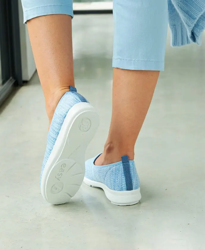 Someone walking away from the camera wearing blue canvas shoes