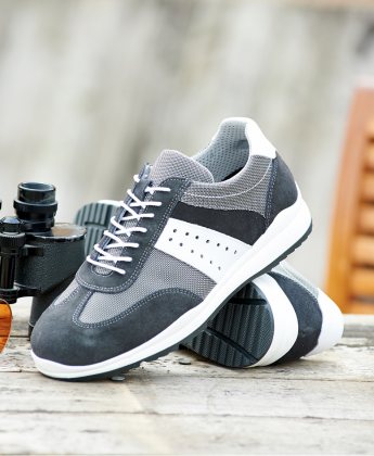 A pair of grey and white trainers on a wooden table next to a pair of binoculars