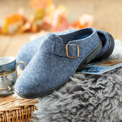 A pair of blue slippers with a buckle on a wooden basket and rug