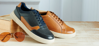 A pair of shoes one navy, one tan, on a table next to sunglasses